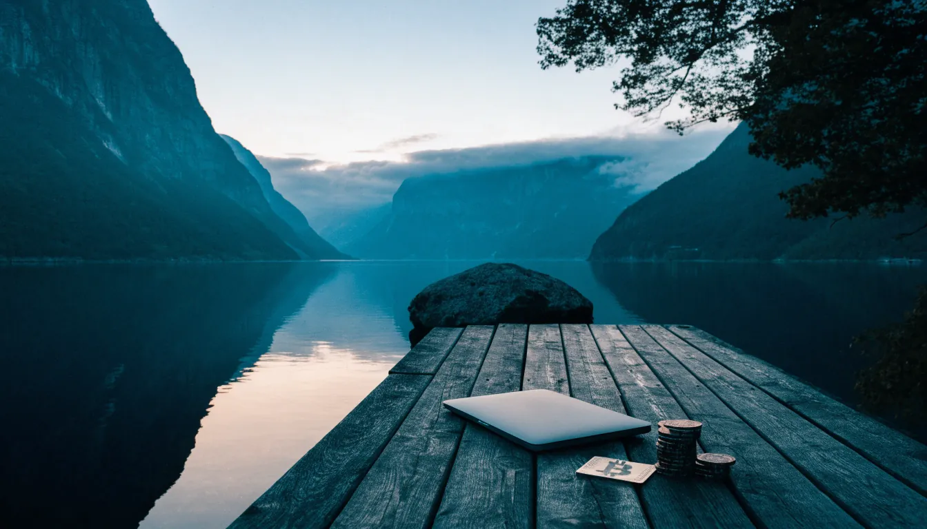 Norsk fjord ved skumring med laptop, Bitcoin-symbol og casinobrikker på en brygge